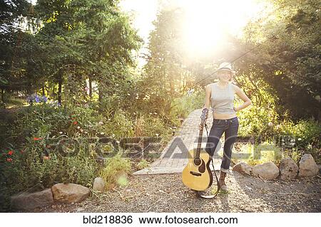 Stock Photograph - Caucasian musician holding guitar in park. Fotosearch
