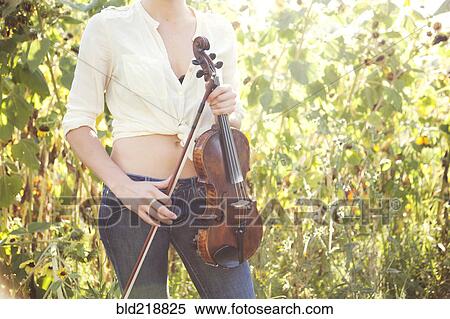 Stock Photography - Caucasian musician holding violin in garden. Fotosearch