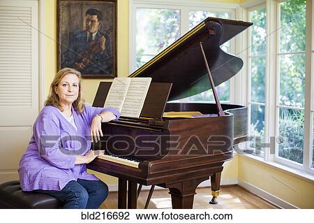 Stock Image - Caucasian musician leaning on piano. Fotosearch