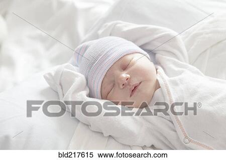 Stock Photography - Caucasian newborn girl laying on bed. Fotosearch