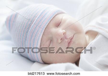 Stock Image - Caucasian newborn girl wearing cap. Fotosearch
