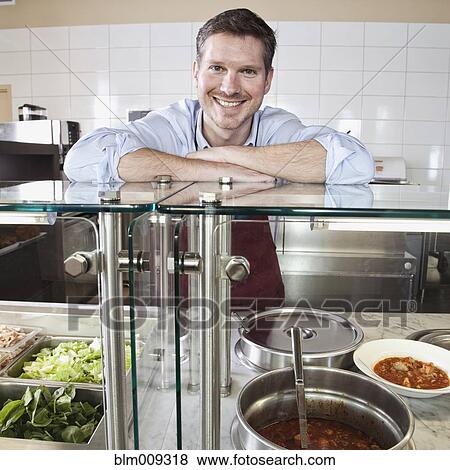 Stock Photo - Caucasian owner leaning on cafe counter. Fotosearch