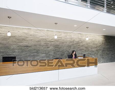 Stock Photo - Caucasian receptionist working at office front desk. Fotosearch