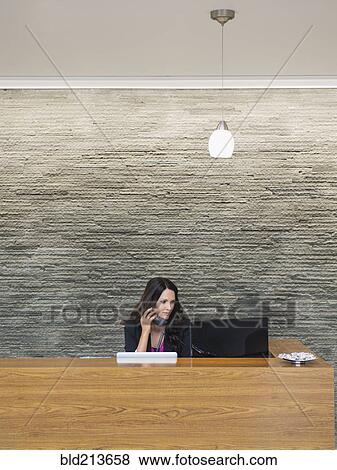 Stock Photo - Caucasian receptionist working at office front desk. Fotosearch