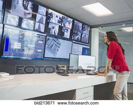 Stock Image - Caucasian security officer watching surveillance cameras. Fotosearch
