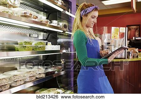 Stock Photograph - Caucasian server using tablet computer in cafe. Fotosearch