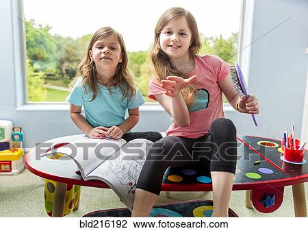 Stock Image - Caucasian sisters drawing at table in playroom. Fotosearch