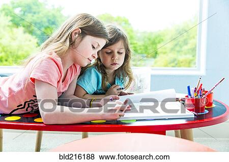 Caucasian sisters drawing at table in playroom View Large Photo Image Stock Photo - Caucasian sisters drawing at table in playroom. Fotosearch