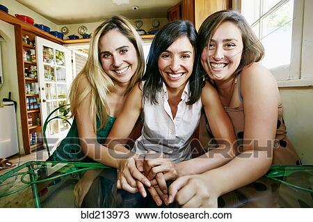 Stock Image - Caucasian sisters hugging in kitchen. Fotosearch