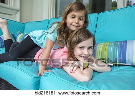 Caucasian sisters playing on sofa View Large Photo Image Stock Image - Caucasian sisters playing on sofa. Fotosearch