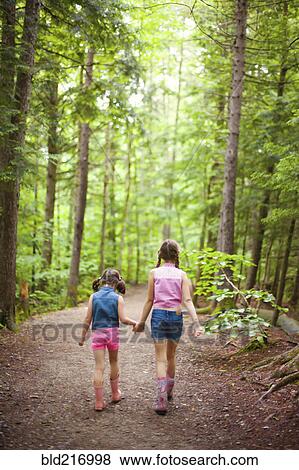 Stock Photo - Caucasian sisters walking in forest. Fotosearch