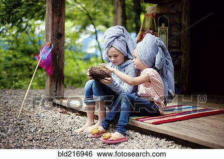 Stock Photograph - Caucasian sisters with hair towels examining bird nest. Fotosearch