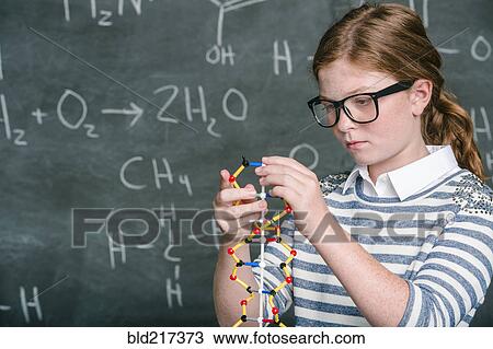 Stock Image - Caucasian student examining molecular model in science class. Fotosearch