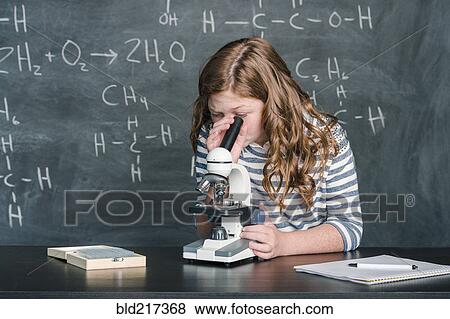 Stock Photo - Caucasian student using microscope in science class. Fotosearch