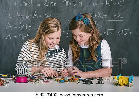 Stock Image - Caucasian students building vehicle in science class. Fotosearch