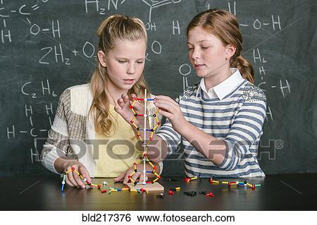 Stock Photograph - Caucasian students examining molecular model in science class. Fotosearch