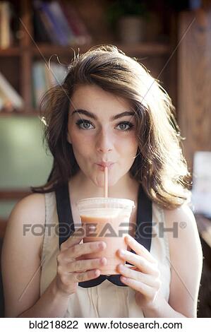 Stock Image - Caucasian teenage girl drinking smoothie in cafe. Fotosearch
