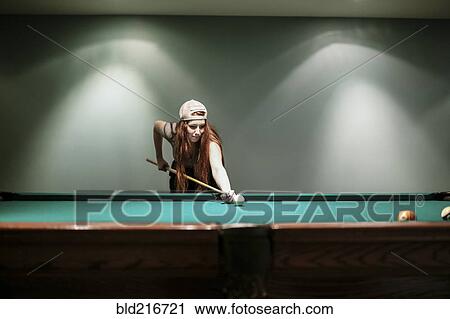 Stock Image - Caucasian teenage girl playing pool. Fotosearch