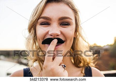 Caucasian teenage girl playing with fake mustache View Large Photo Image Stock Photo - Caucasian teenage girl playing with fake mustache. Fotosearch
