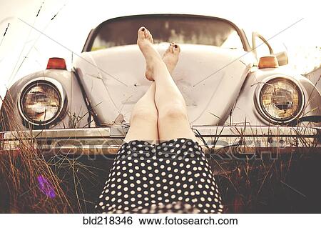 Stock Photograph - Caucasian teenage girl resting feet on vintage car. Fotosearch