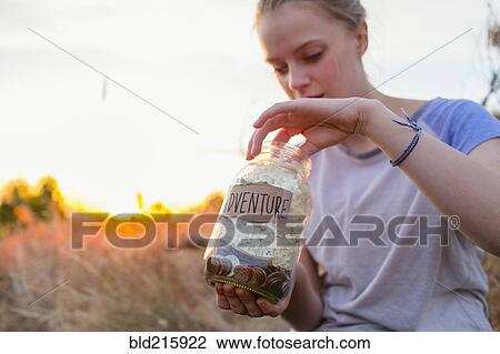Caucasian teenage girl saving money in jar View Large Photo Image Stock Image - Caucasian teenage girl saving money in jar. Fotosearch