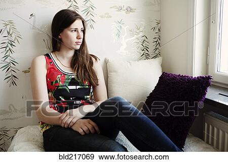 Stock Photo - Caucasian teenage girl sitting on bed. Fotosearch