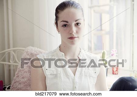 Stock Photo - Caucasian teenage girl sitting on bed. Fotosearch