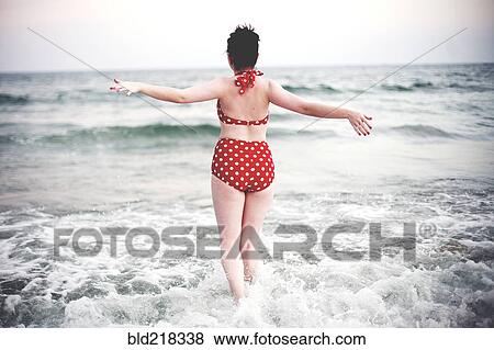 Stock Photo - Caucasian teenage girl splashing in ocean waves. Fotosearch