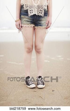 Stock Photo - Caucasian teenage girl standing on beach. Fotosearch