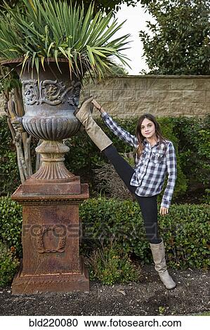 Stock Image - Caucasian teenage girl stretching leg in backyard. Fotosearch