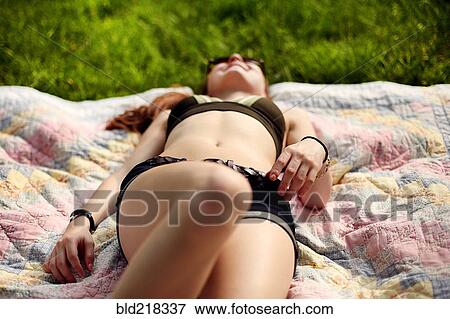 Stock Photo - Caucasian teenage girl sunbathing on blanket. Fotosearch
