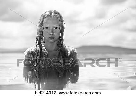 Stock Image - Caucasian teenage girl swimming in lake. Fotosearch