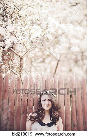 Stock Photo - Caucasian teenage girl wearing flower crown near wooden fence. Fotosearch