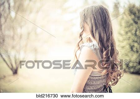 Stock Image - Caucasian teenage girl with curly hair outdoors. Fotosearch