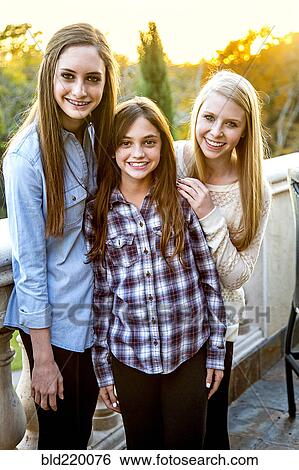Stock Photograph - Caucasian teenage girls smiling on patio. Fotosearch