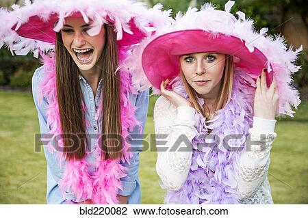 Stock Image - Caucasian teenage girls wearing feather boas and hats. Fotosearch