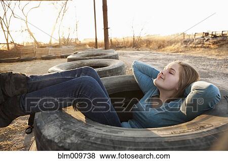 Stock Photo - Caucasian teenager sitting in large tire. Fotosearch