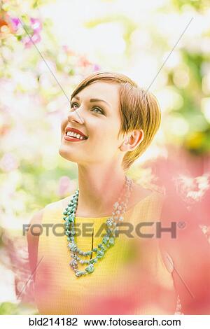 Caucasian woman admiring flowers in garden View Large Photo Image Stock Image - Caucasian woman admiring flowers in garden. Fotosearch