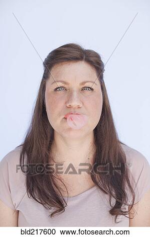 Stock Image - Caucasian woman blowing bubble with gum. Fotosearch