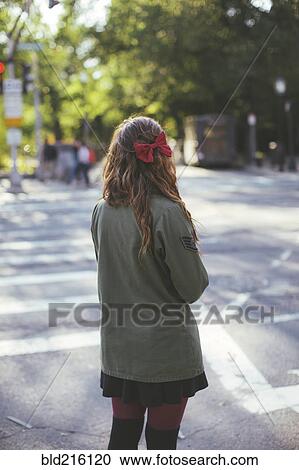 Stock Image - Caucasian woman crossing city intersection. Fotosearch