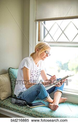 Stock Photography - Caucasian woman drawing in windowsill. Fotosearch