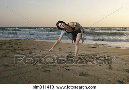 Caucasian woman drawing on beach sand View Large Photo Image Stock Image - Caucasian woman drawing on beach sand. Fotosearch