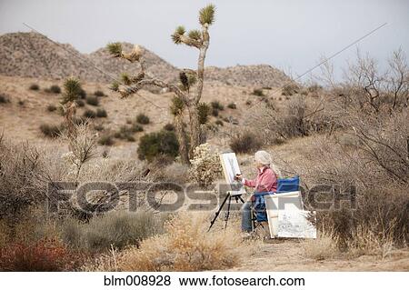 Stock Photo - Caucasian woman drawing on easel outdoors. Fotosearch