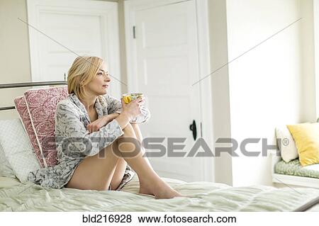 Caucasian woman drinking coffee on bed View Large Photo Image Stock Photo - Caucasian woman drinking coffee on bed. Fotosearch
