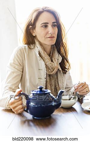Stock Photo - Caucasian woman drinking tea at table. Fotosearch