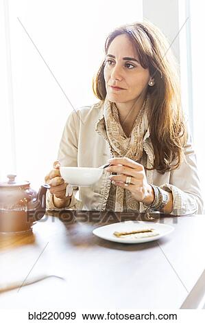 Stock Photo - Caucasian woman drinking tea at table. Fotosearch