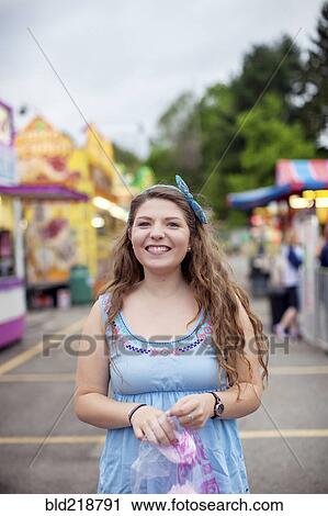 Stock Image - Caucasian woman eating candy at amusement park. Fotosearch