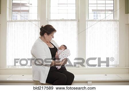 Caucasian woman holding baby granddaughter in windowsill View Large Photo Image Stock Photo - Caucasian woman holding baby granddaughter in windowsill. Fotosearch