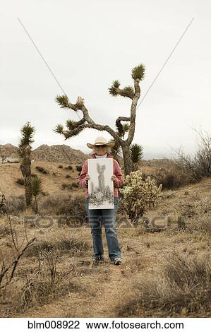 Stock Image - Caucasian woman holding drawing outdoors. Fotosearch