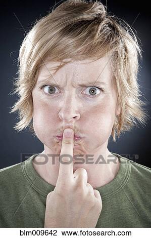 Stock Image - Caucasian woman holding finger over her mouth. Fotosearch